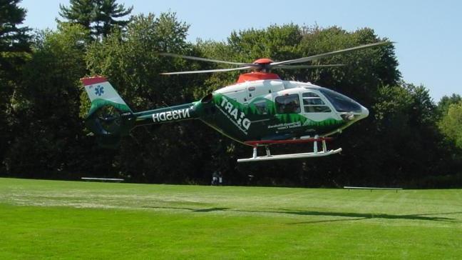A DHART helicopter lands on a field.